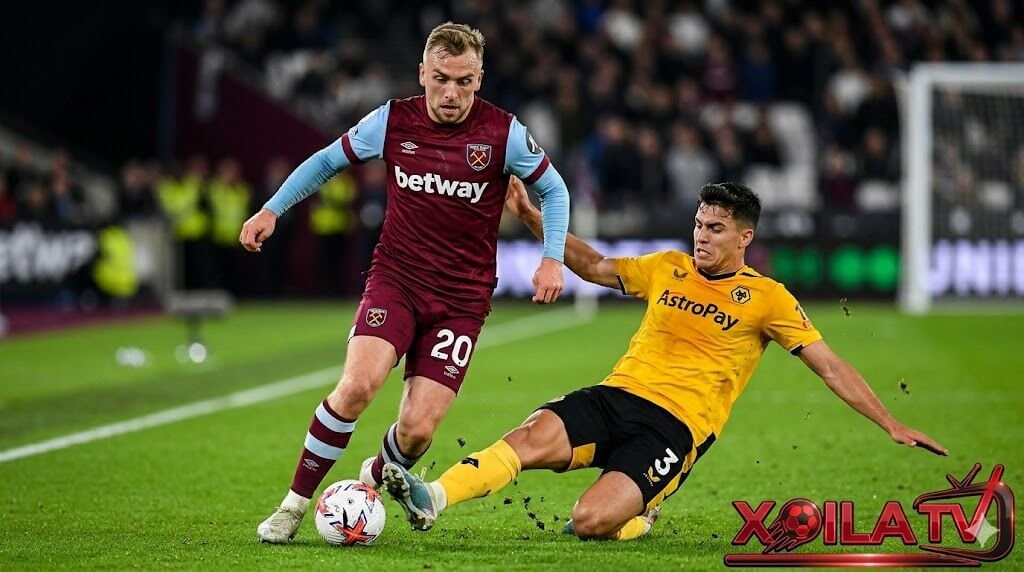 Xoilac TV diem nong tran dau West Ham vs Wolves, hinh anh can canh Jarrod Bowen (West Ham, so 20) dốc bóng va cắt chéo vao khu vực half-space, cơ bắp căng thẳng và mồ hôi rơi, đang đối đầu trực tiếp voi Santiago Bueno (Wolves, so 3) đang xoạc bóng va truy cản quyết liệt. Cả hai cầu thủ thể hiện sự quyết tâm tột độ, biểu cảm gương mặt căng thẳng